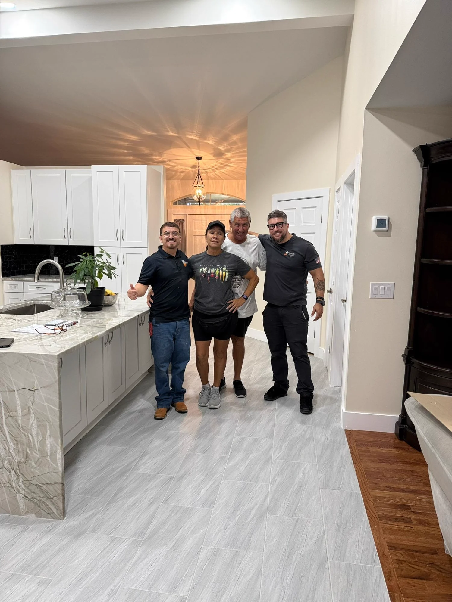 Emmanuel Nunes (left) and Bernardo Nunes (right), owners of Nunes 4 Flooring, with homeowners after a kitchen tile floor installation and remodel in Jacksonville, FL