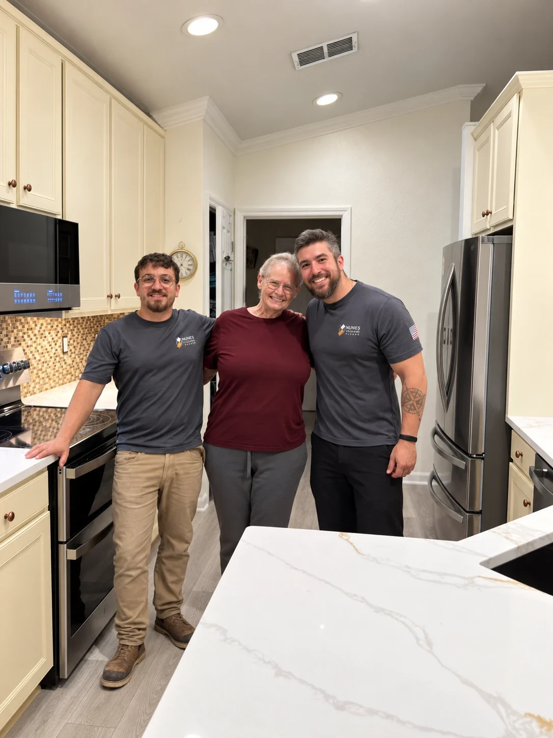 Emmanuel Nunes (left) and Bernardo Nunes (right) with a happy client in her remodeled kitchen with new luxury vinyl plank flooring in Jacksonville, FL