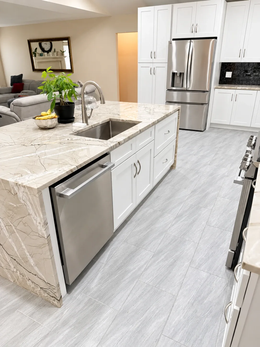 Quartzite waterfall island with undermount sink, white shaker cabinets and wood-look porcelain tile floor, kitchen remodel in Avondale Jacksonville FL