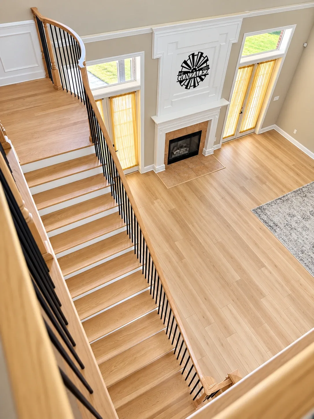 Remodeled oak staircase with iron balusters overlooking a great room with light wood-look floors, Orange Park
