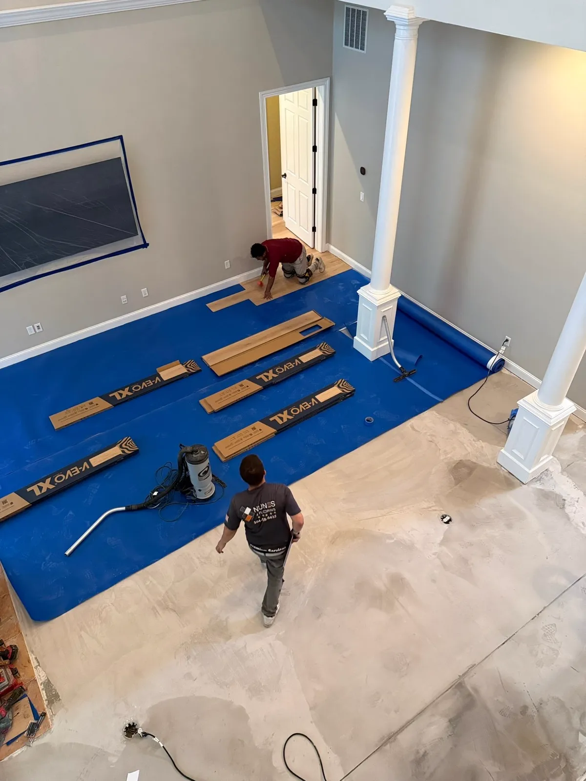 Nunes 4 Flooring crew installing wide-plank flooring over a leveled slab in a two-story great room, Orange Park FL