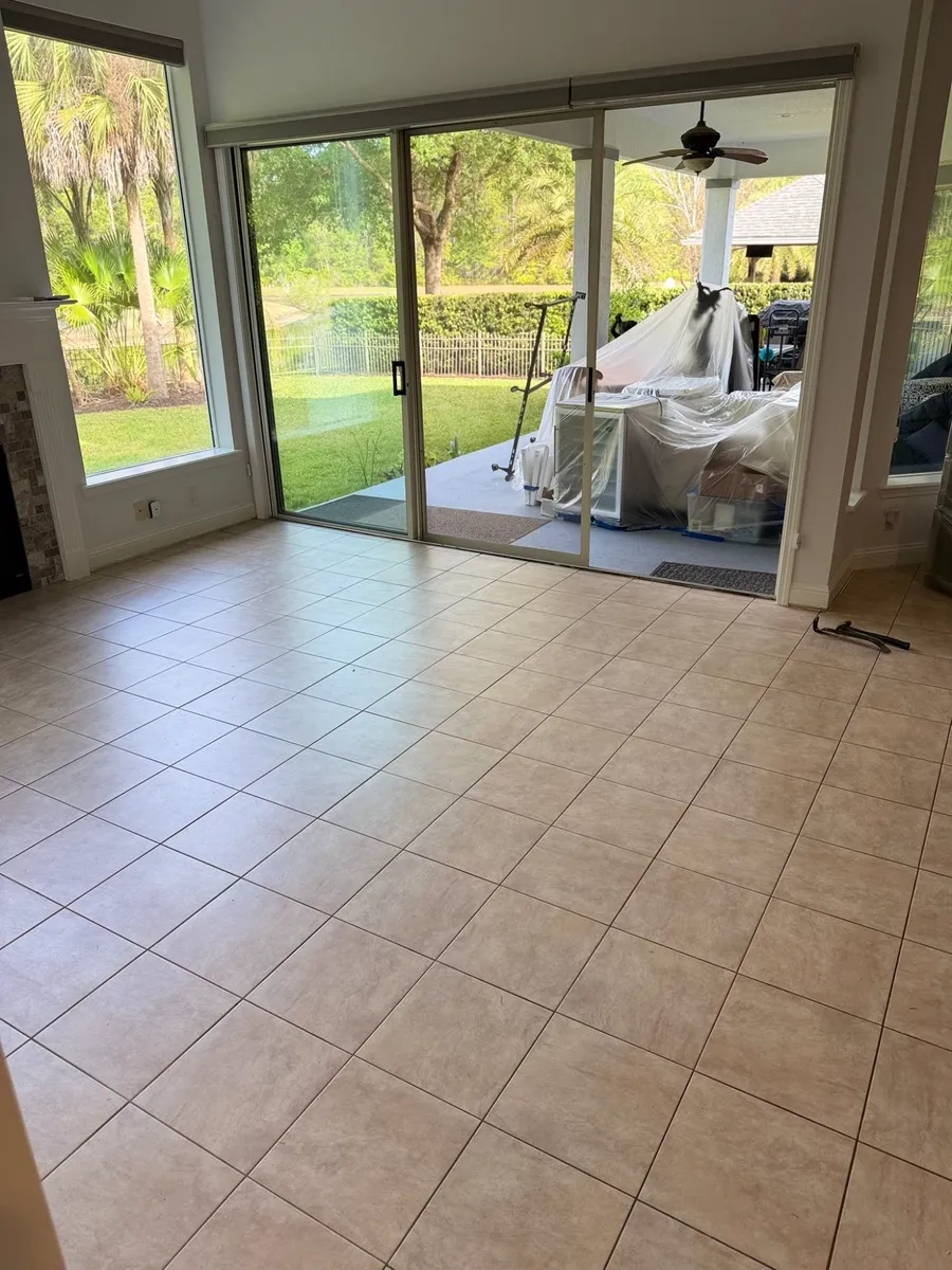 Before: beige ceramic tile floor in a living room with sliding glass doors and fireplace in Fernandina Beach, FL