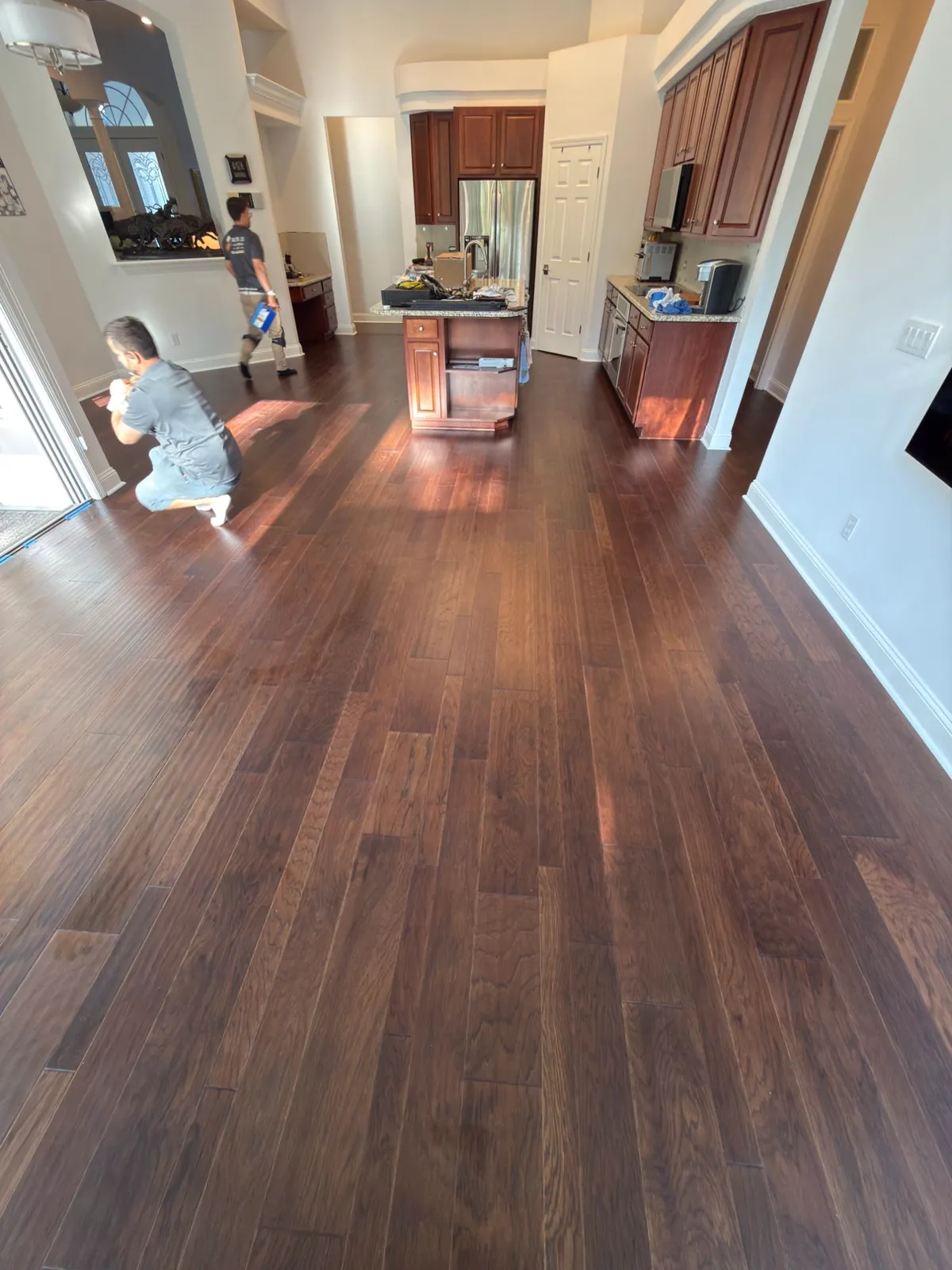 Nunes 4 Flooring crew finishing a glue-down hickory hardwood installation in a kitchen in Fernandina Beach, FL