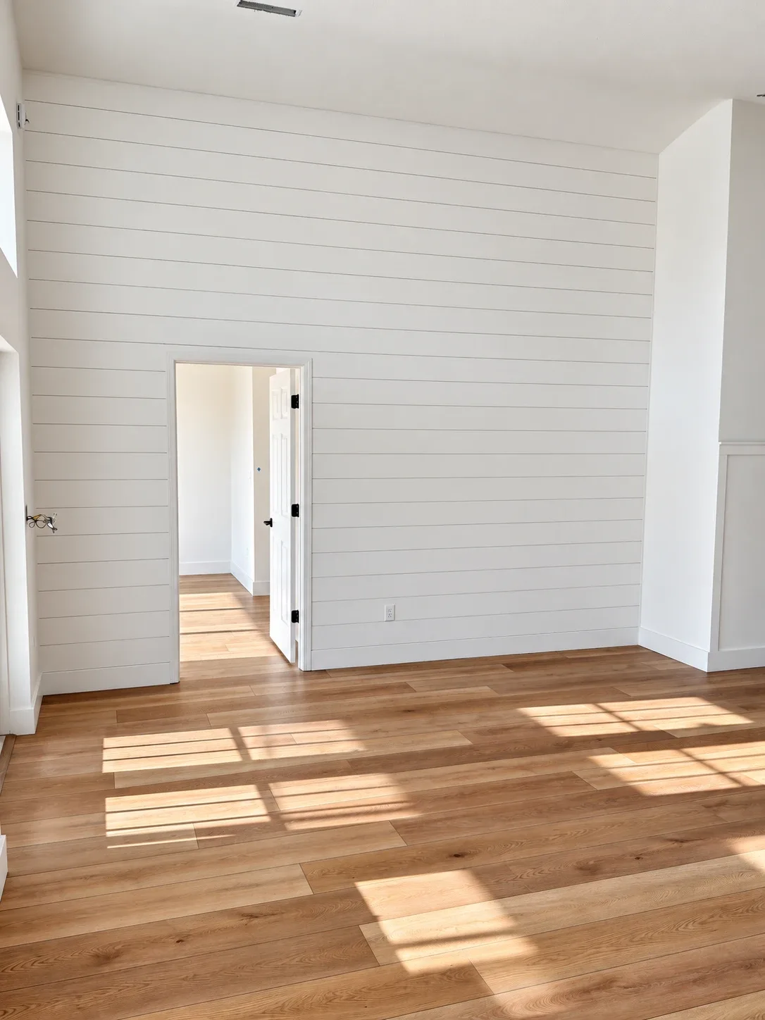 Bedroom with white shiplap accent wall and wide-plank luxury vinyl flooring, whole-home remodel in St. Augustine Beach FL