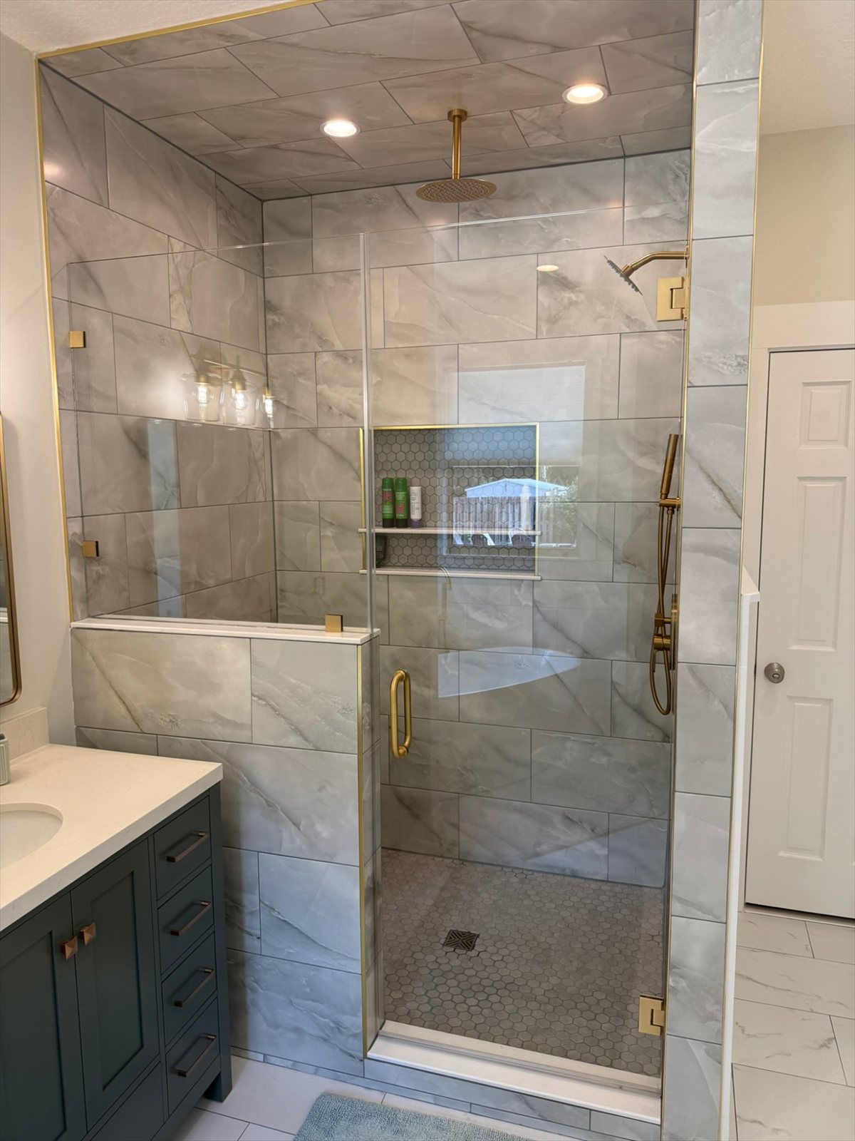 Bathroom remodel in Jacksonville, FL — marble-look tile walk-in shower with brushed gold fixtures by Nunes 4 Flooring