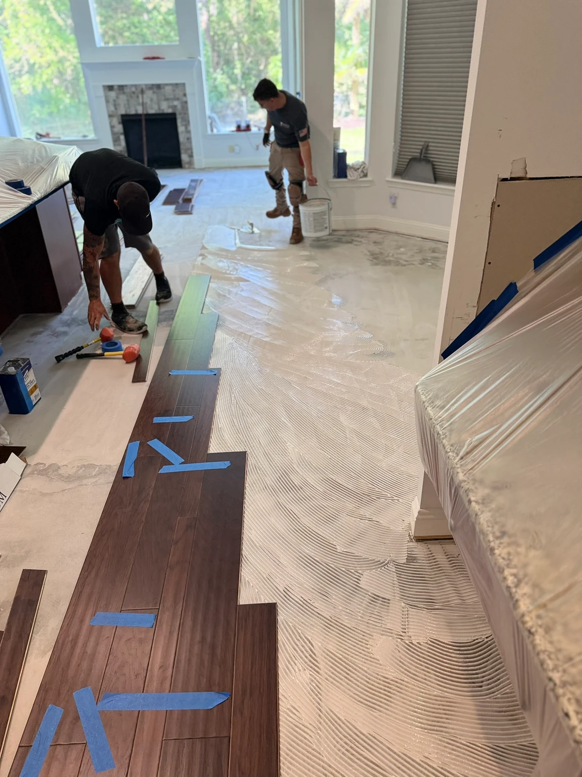 Nunes 4 Flooring installers placing wood planks beside freshly troweled adhesive in a Fernandina Beach home